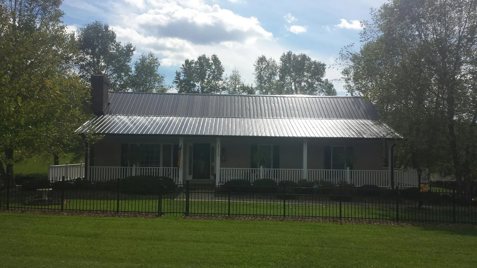 Gray metal roof on a brick ranch with a full width front porch — Gutter Guard Installation work by our crew in Middlesex