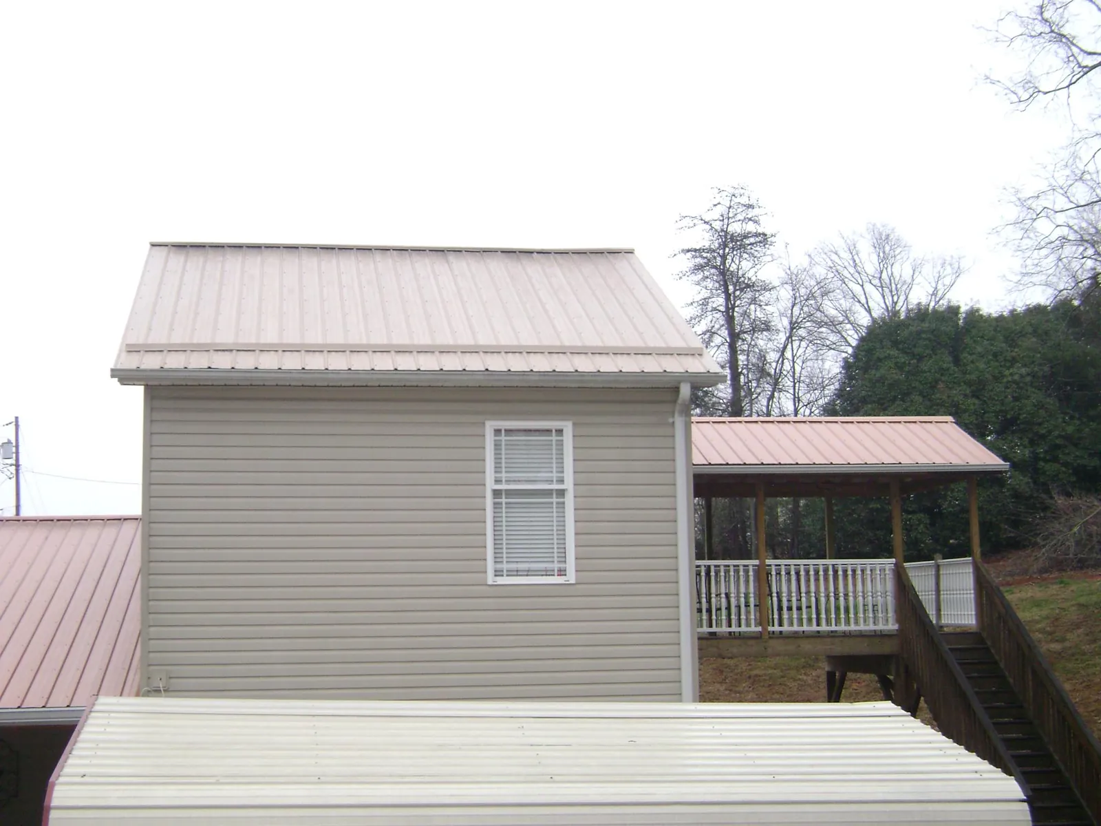 Tan metal roofs on a two story addition and attached porch, from a Roof Replacement job in Middlesex